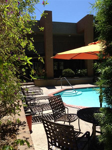 A poolside area with chairs and an umbrella.