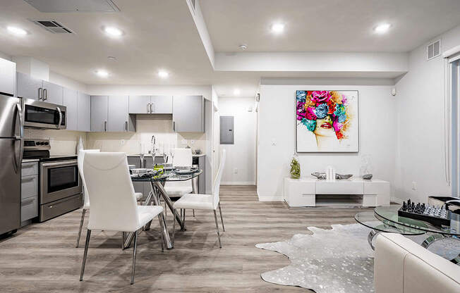 Luxurious interior of a unit, living room in the right, dining area, Open kitchen on the left with stainless steel appliances, laminate flooring throughout, recessed lighting