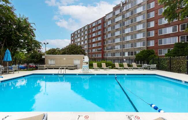 A large swimming pool in front of a red brick building.