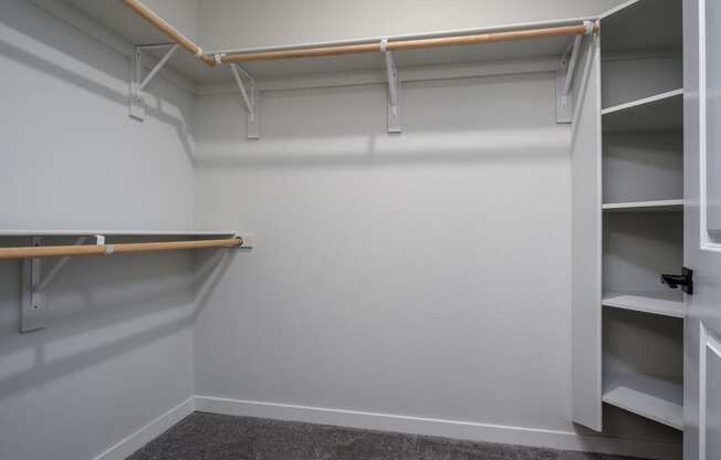 a walk in closet with shelves and a hanger on the wall