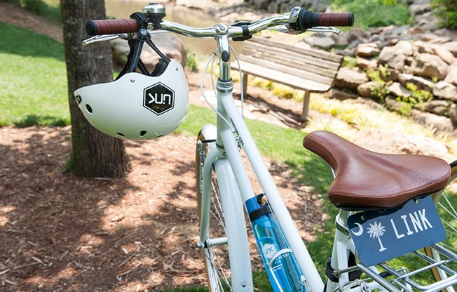 a bike parked in a park with a helmet on the handlebars at Link Apartments® Canvas, Georgia