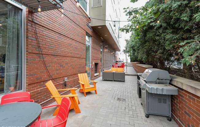 a patio with chairs and a grill on the side of a building