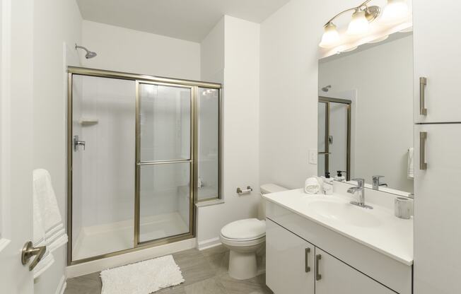 a white bathroom with a shower toilet and sink