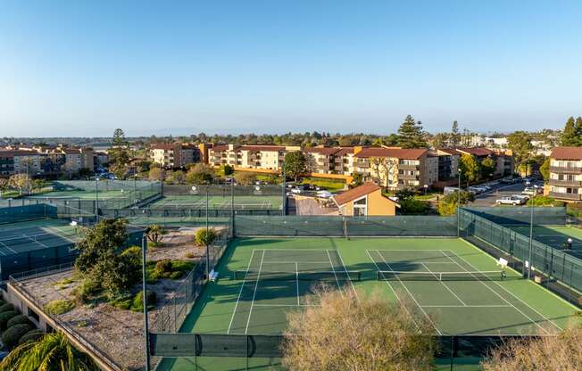 two tennis courts on the roof of a building with a city in the background