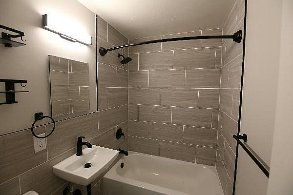 Modern bathroom with sleek gray tile, elegant fixtures, and a spacious bathtub.