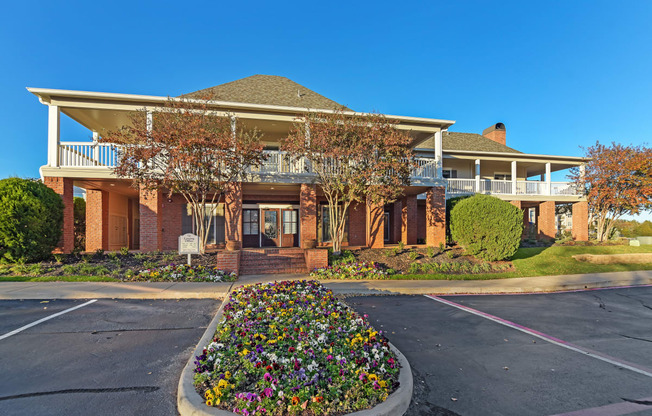 a house with a driveway and a flower garden in front of it at Cumberland Place Apartment Homes, Tyler, Texas
