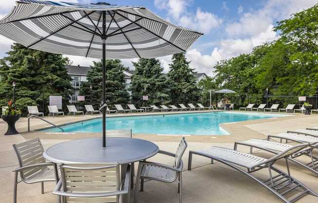 A pool area with a table and chairs and an umbrella