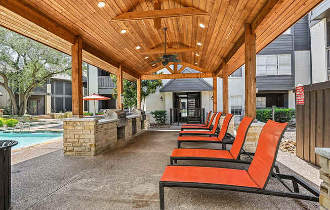 A row of orange chairs are lined up on a patio.