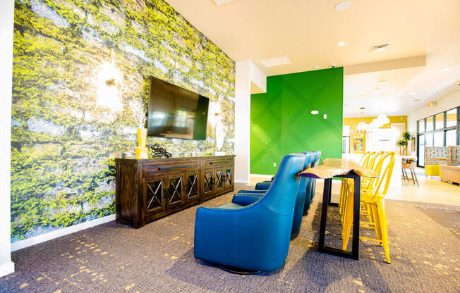 a lobby with blue chairs and a table and a television