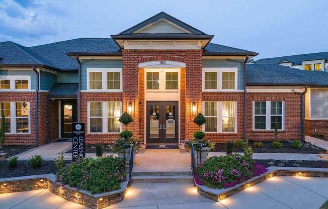 the front of a brick house with a driveway and landscaping
