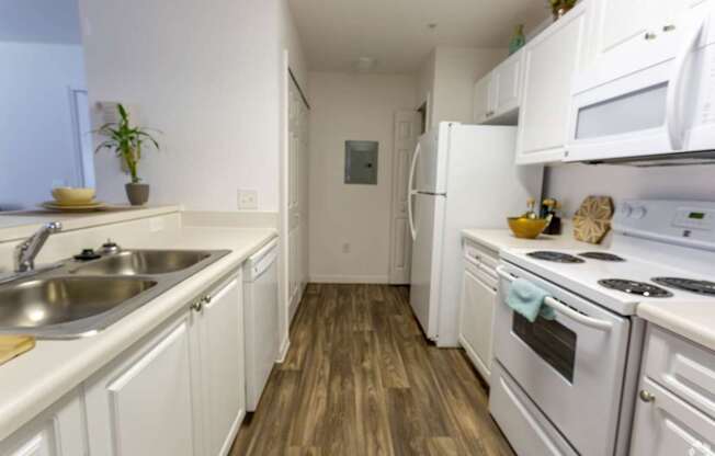 A kitchen with white appliances and wooden floors.