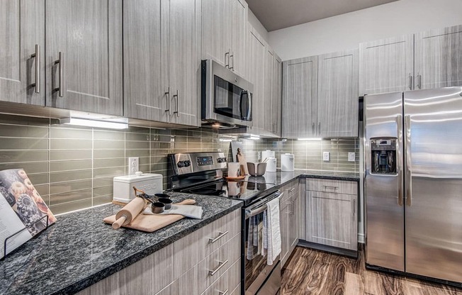 Granite counter tops, stainless appliance package, medium brown cabinets, plank wood-style flooring, island seating, abundant cabinet and pantry space