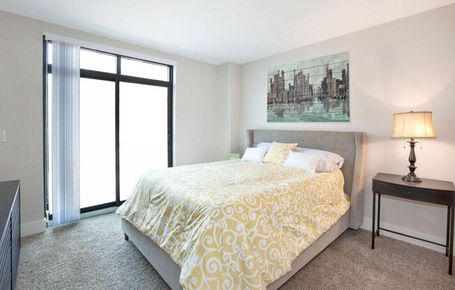 a bedroom with a yellow bedspread and a painting on the wall