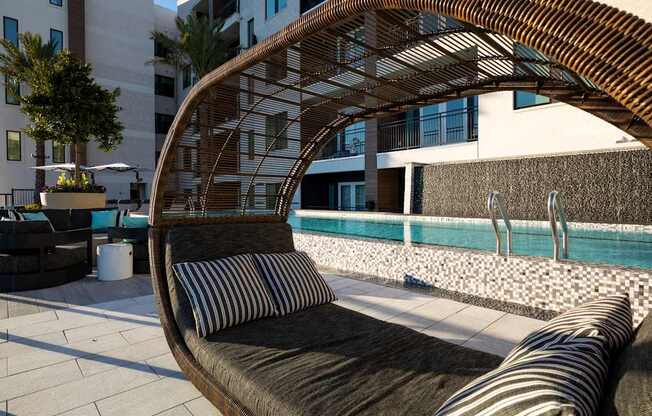 A wooden outdoor sofa with a striped cushion sits on a patio.