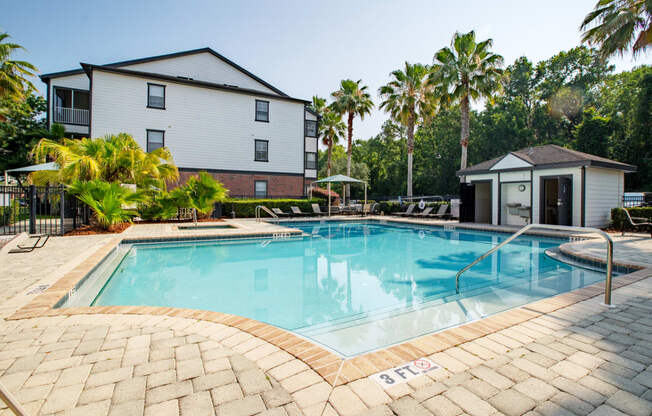 a swimming pool with apartments in the back and palm trees