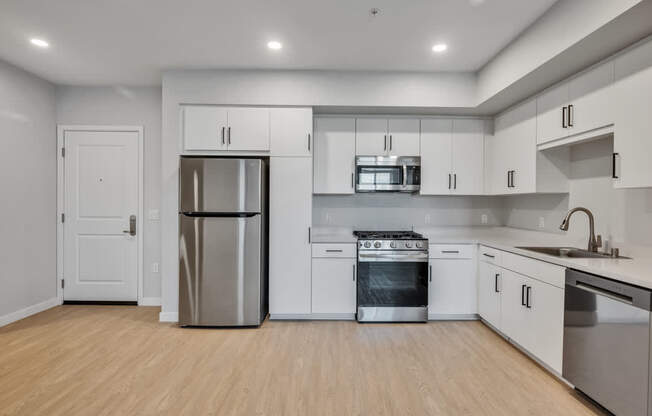 A modern kitchen with stainless steel appliances and wooden flooring.