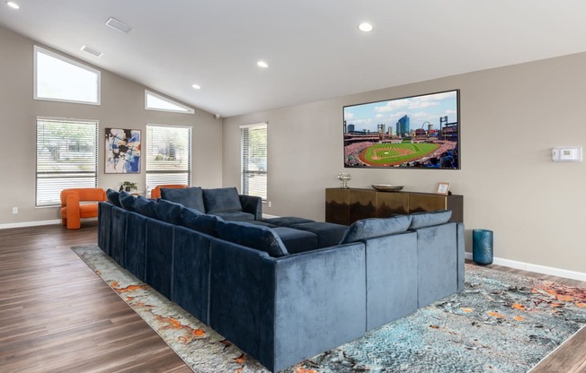 a living room with a blue couch and a tv on the wall