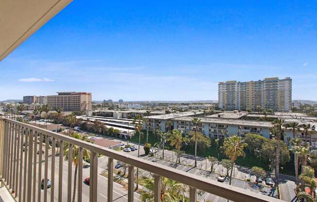 A balcony overlooks a cityscape with buildings and palm trees.