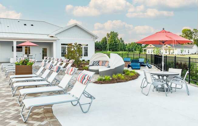 a patio with lounge chairs and umbrellas at the enclave at woodbridge apartments in sugar