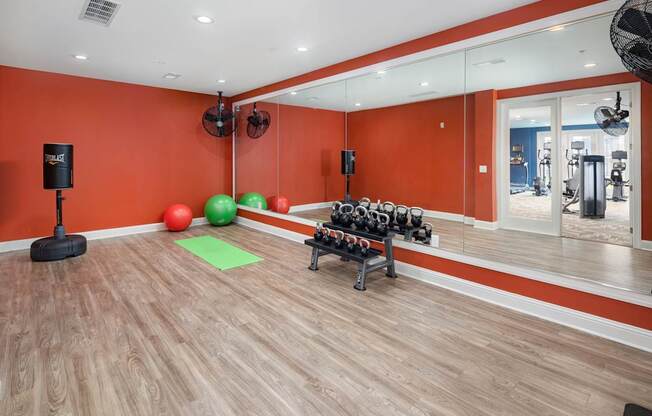 A gym with orange walls and wooden floors.