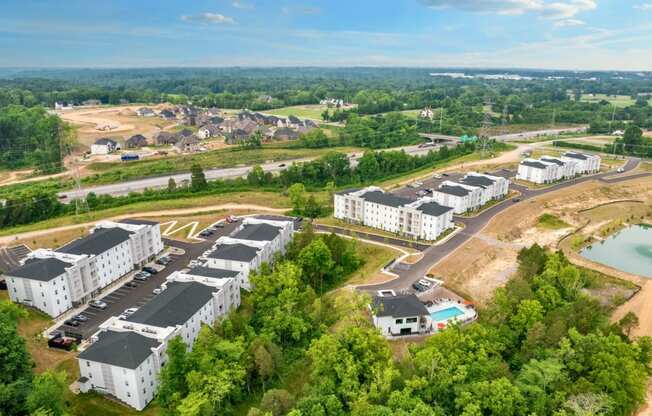 an aerial view of an apartment complex with a pool and trees