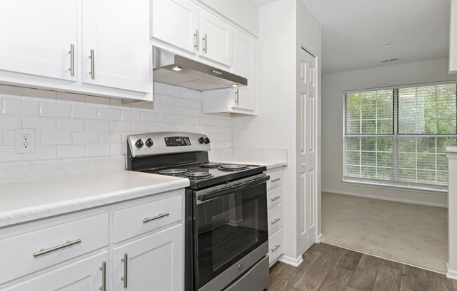 a kitchen with white cabinets and a stainless steel black stove top oven at Canopy at Baybrook apartments in Charlotte NC