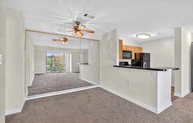 A spacious living room with a ceiling fan and a kitchen.