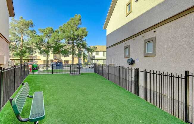 A small green park with a bench and a fence.