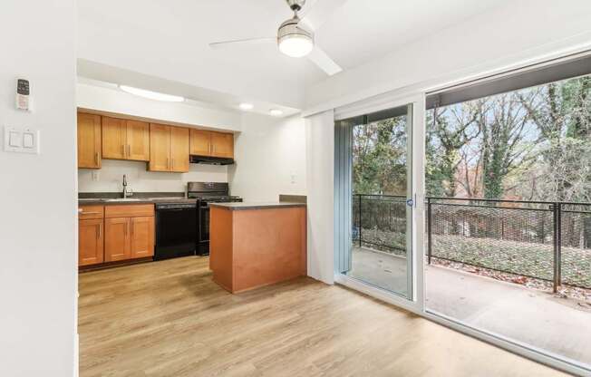 an empty living room with a sliding glass door to a kitchen