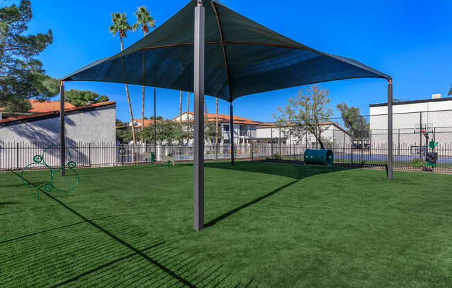 a large shade sail in a backyard with a playground