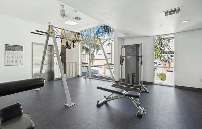 A gym with a weight bench, a pull up bar and a window.