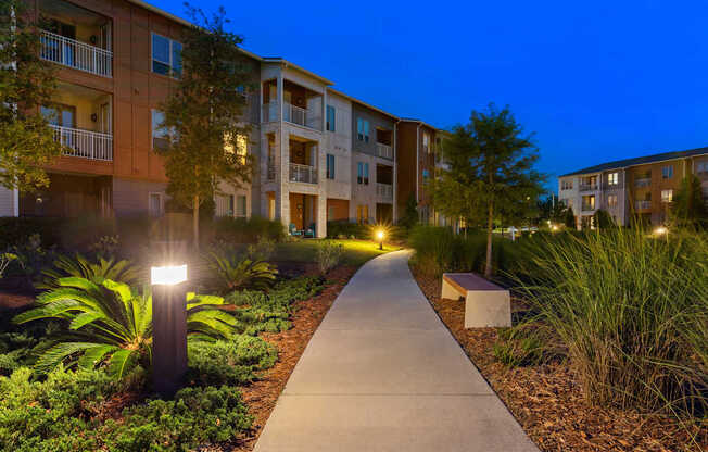 A walkway leads through a landscaped area in front of apartment buildings.