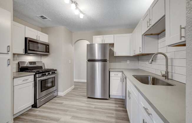 a kitchen with white cabinets and stainless steel appliances