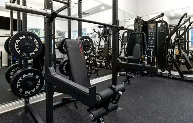 A gym with a squat rack and a weight bench.