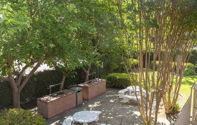 a backyard with a patio and trees and a white fence