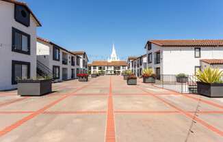 an empty parking lot with buildings and a church in the background