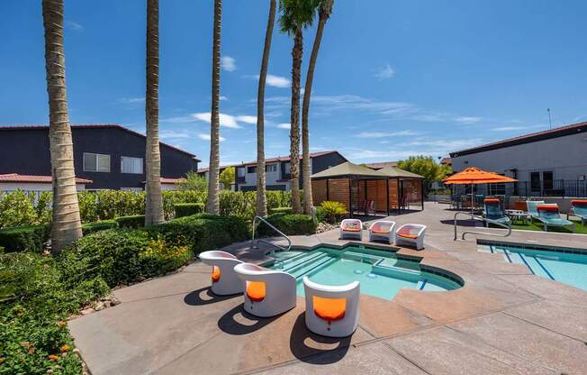 A pool surrounded by palm trees and orange chairs.