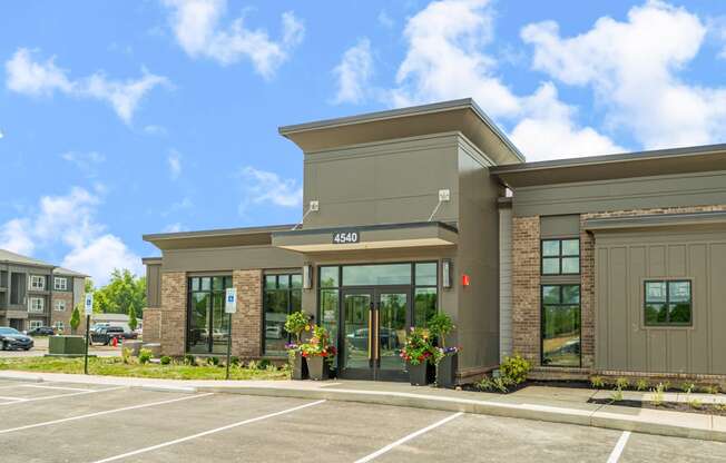 the front of a building with glass doors and a parking lot