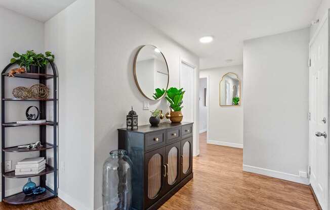 A hallway with a black cabinet and a mirror on the wall.