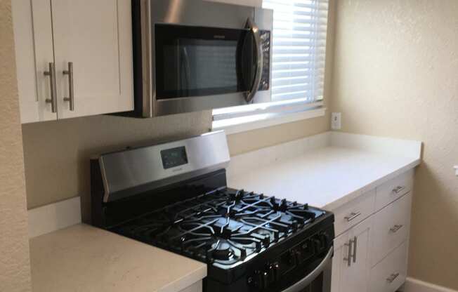 a kitchen with white cabinets and a stove and a microwave