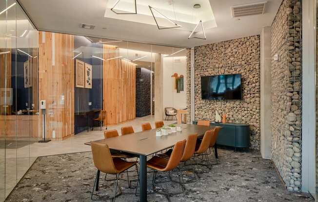 A conference room with a stone wall and a long table with chairs.