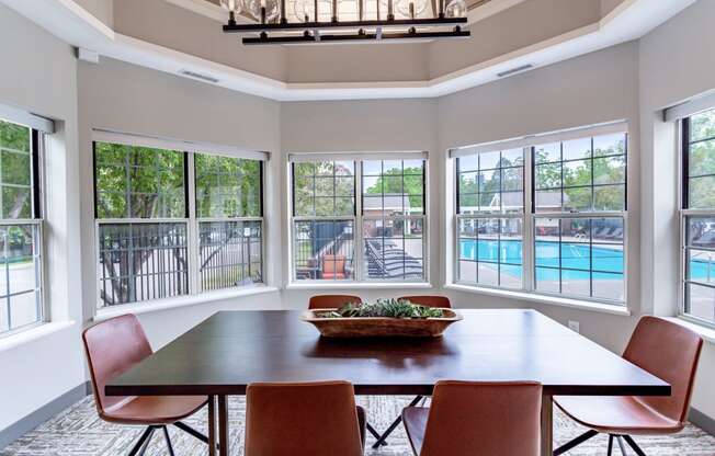 a dining room with a table and chairs with a view of a pool in the background