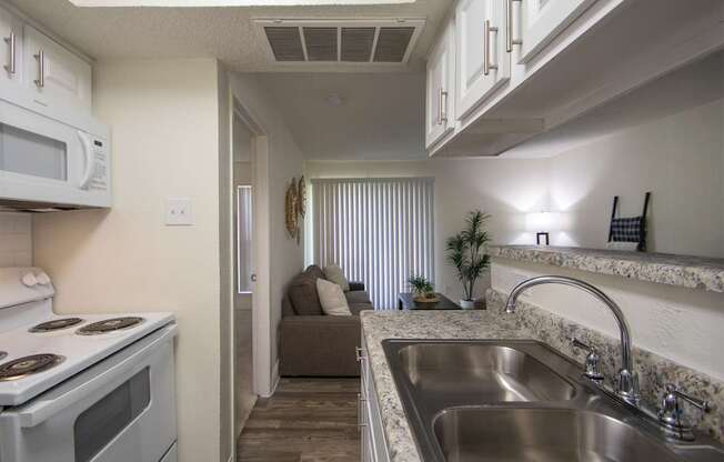 A kitchen with a white cabinets and appliances in a 515 square foot 1 bedroom, 1 bath apartment home at Canyon Creek Apartments in Dallas Midtown neighborhood of Dallas, TX.