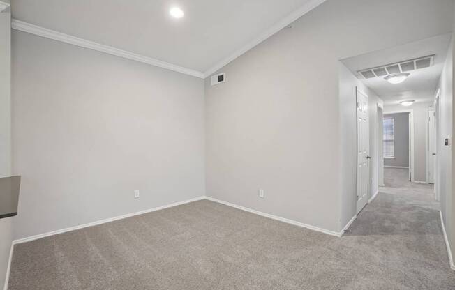 A spacious room with carpeted floor and white walls.