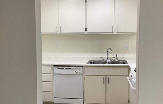 A kitchen with white cabinets and a wooden floor.