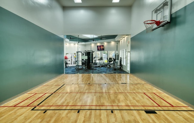 the court in the gym with a basketball hoop and a scoreboard