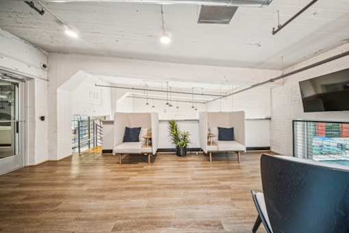 A room with a wooden floor and a white wall with a TV mounted on it.