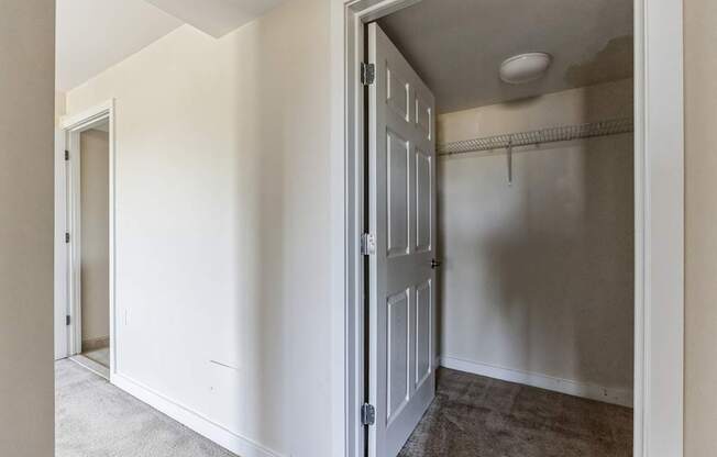 an empty bedroom with a closet and a door to a hallway