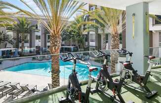 A gym with exercise bikes and a pool in the background.
