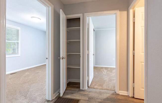 A white closet with a door open to a room.